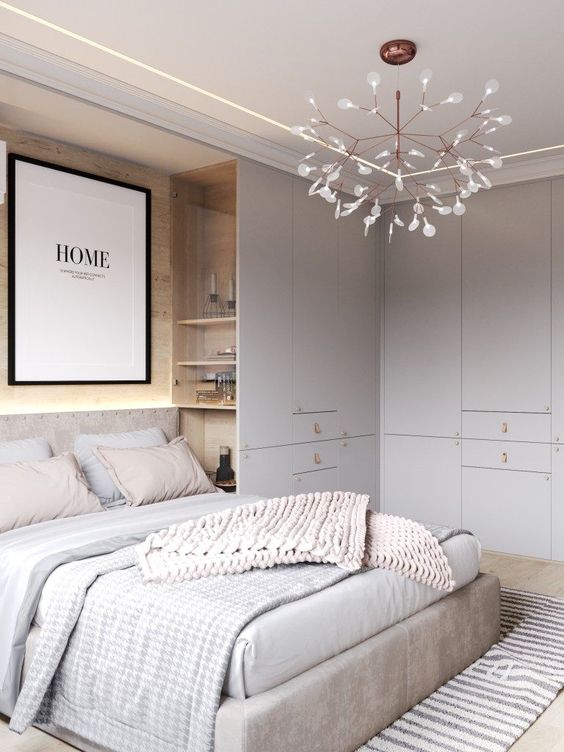A neutral bedroom with light grey, off white and touches of blush, built in storage units and shelves