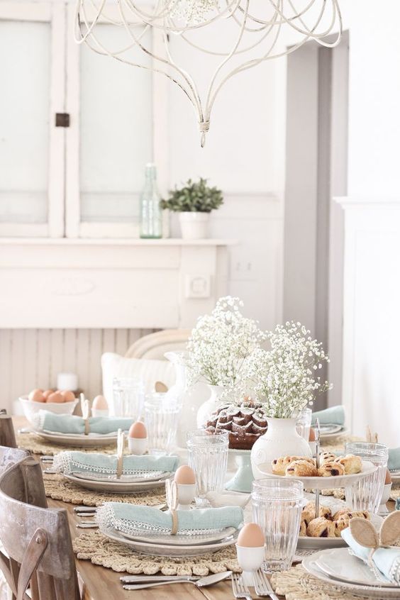 a pastel vintage-inspired tablescape with a baby's breath centerpiece, wicker chargers, blue napkins and bunny ear napkin rings