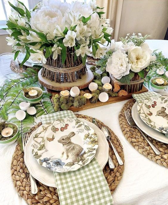 a rustic Easter tablescape with a tray with moss, egg shell candles, white blooms and greenery, woven palcemats and printed plates, checked napkins