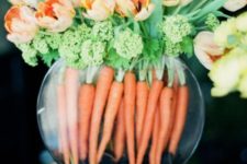 a simple Easter arrangement of carrots, greeneyr and orange tulips in a large rounded vase