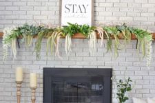a spring mantel with cascading florals and greenery plus a sign, fake eggs in a lantern by the fireplace