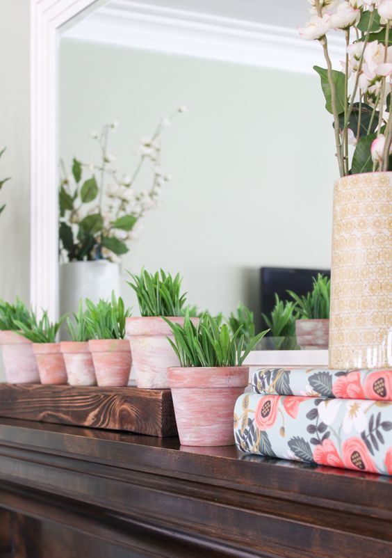 a spring mantel with potted greenery, blooming branches and floral print paper