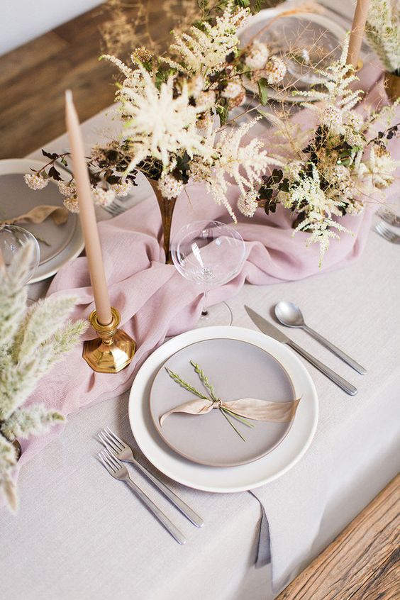 a tender spring tablescape done in the shades of pink, with matte porcelain, blush candles and spring blooms in vases