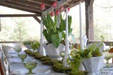 a thrifted spring table setting with pink tulips, grene glasses, a moss runner and a greenery centerpiece