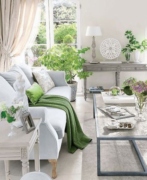 a vintage farmhouse living room with pastel and wooden furniture, potted greenery and blooms and refined art