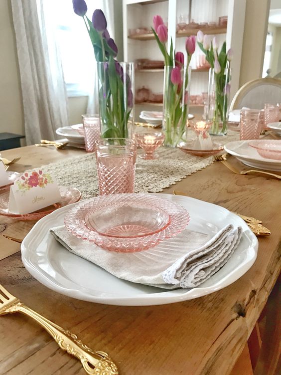 A vintage inspired spring tablescape with pink glass, pink tulips in vases and a lace table runner