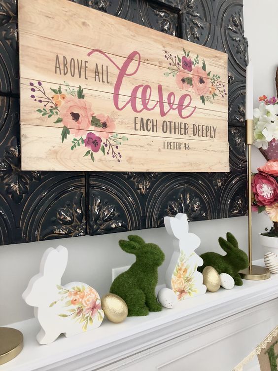 A whimsy Easter mantel with a large floral sign, some bunnies   of moss and with floral prints and some faux eggs