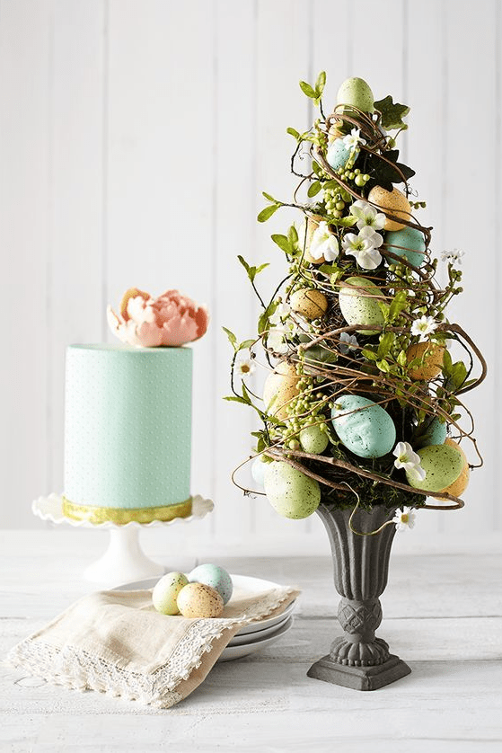 An Easter flower arrangement designed as a tree   with vines, greenery, blooms and pastel eggs