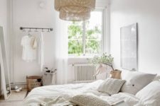 an airy Nordic bedroom with a wicker lampshade, crochet pillows, neutral furniture and much light