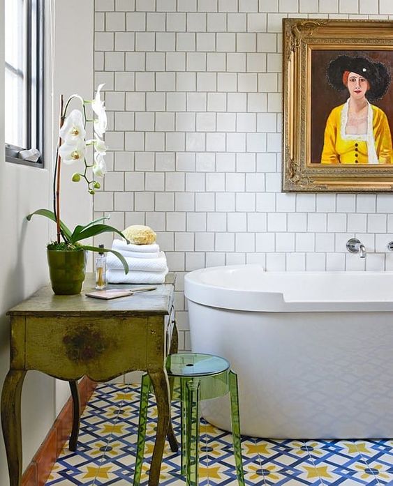 an eclectic bathroom with a colorful tile floor, a vintage vanity and an acrylic stool plus a white orchid for a refined touch