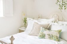 fresh greenery in pots and botanical pillows make the neutral space feel like spring and make it inviting