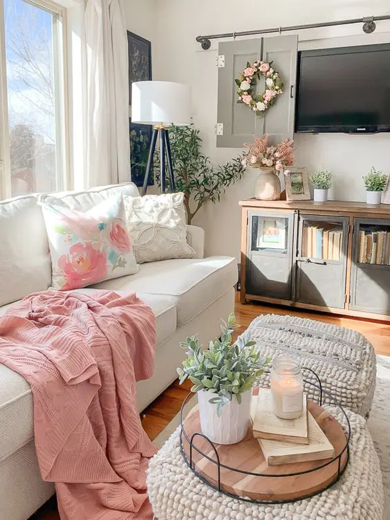 pink and floral textiles, potted greenery and faux blooms and candles make the neutral living room more chic