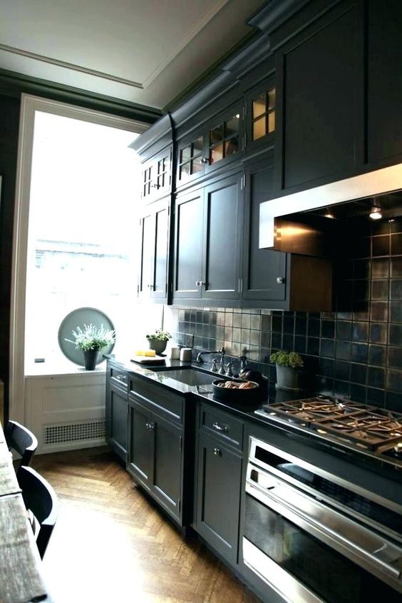 a black kitchen island with vintage cabinets, tiles, lights for a stylish masculine feel in the kitchen