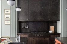 a black stone kitchen with a backsplash, a colorful kitchen island with a stone countertop and pendant lamps