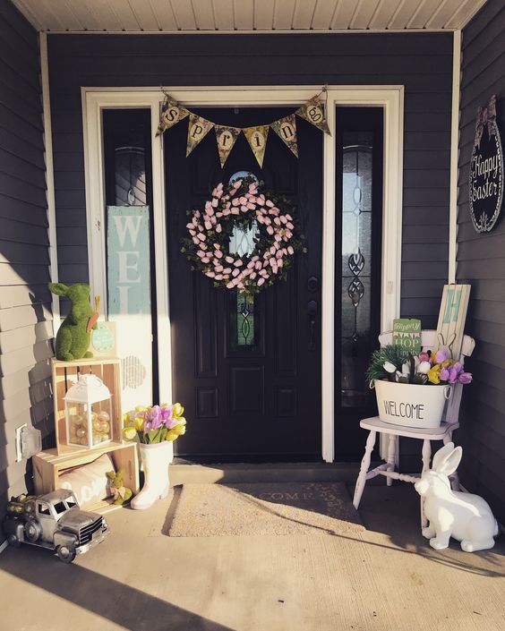 a bright spring Easter porch with a pink tulip wreath, a bunting, bunnies of moss and wood, tulips in buckets