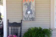 a bunny and carrot sign, potted cascading greenery and potted blooms and a faux bunny for porch decor