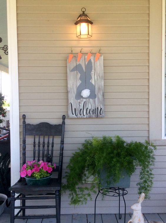 a bunny and carrot sign, potted cascading greenery and potted blooms and a faux bunny for porch decor