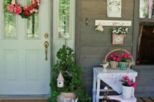 a colorful Easter porch with a bright bloom wreath, potted flowers, bunnies and a little bird house