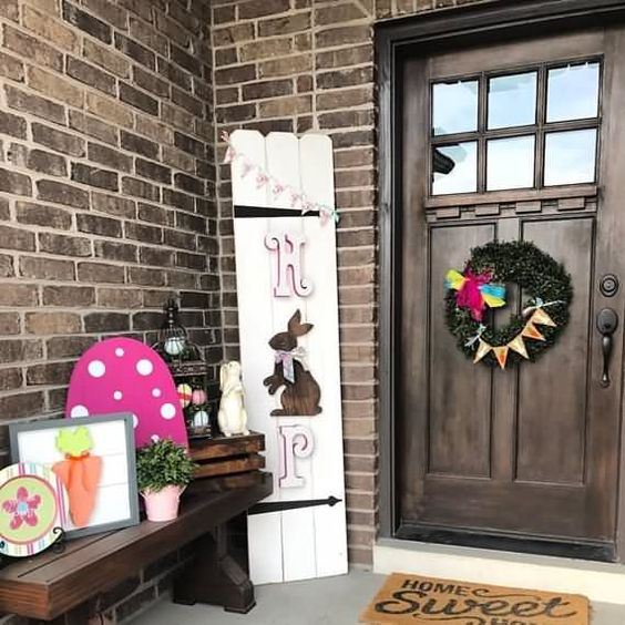 a colorful Easter porch with some themed artworks, a greneery wreath and a HOP and bunny sign