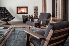 a contemporary living room with dark furniture, a built-in fireplace and firewood storage, a dark rug and a coffee table