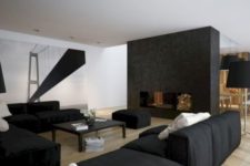 a contemporary masculine living room with a fireplace, black furniture, a large artwork and a black coffee table