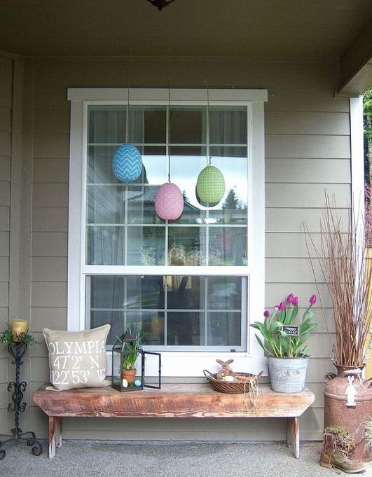 a cozy Easter front porch with potted tulips, colorful eggs, a lantern with greenery and eggs and a bunny