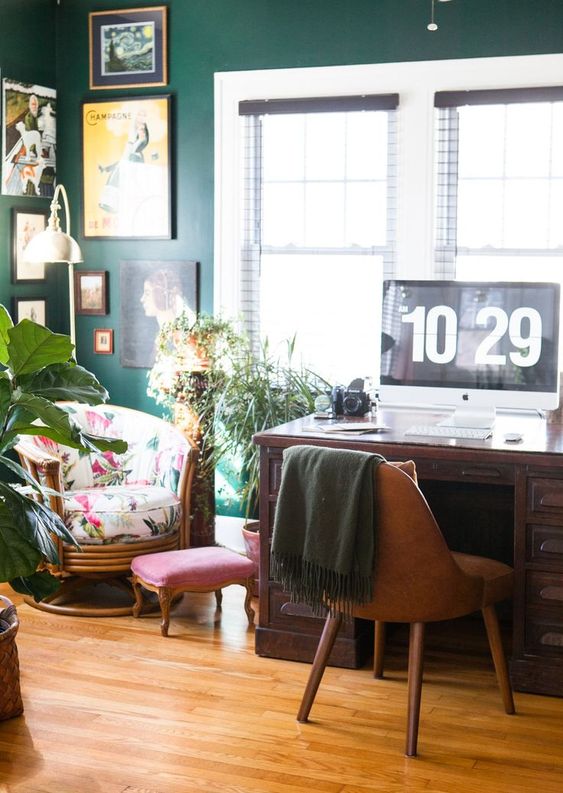 a deep green wall, a bright printed chair and some potted greenery make the home office spring-filled
