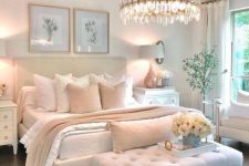 a glam and feminine bedroom with neutral furniture, a statement crystal chandelier, botanical artworks and real blooms