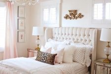 a glam girlish bedroom with an upholstered bed, mirrored nightstands and a bench, a crystal chandelier and touches of light pink