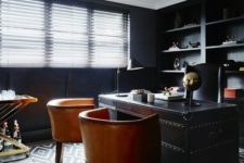 a gorgeous masculine home office with black walls, a black metal desk with amber leather chairs and shiny metallic touches