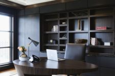 a minimalist and refined home office with a black built-in shelving unit, a sculptural oval desk of rich stained wood, a bold chandelier