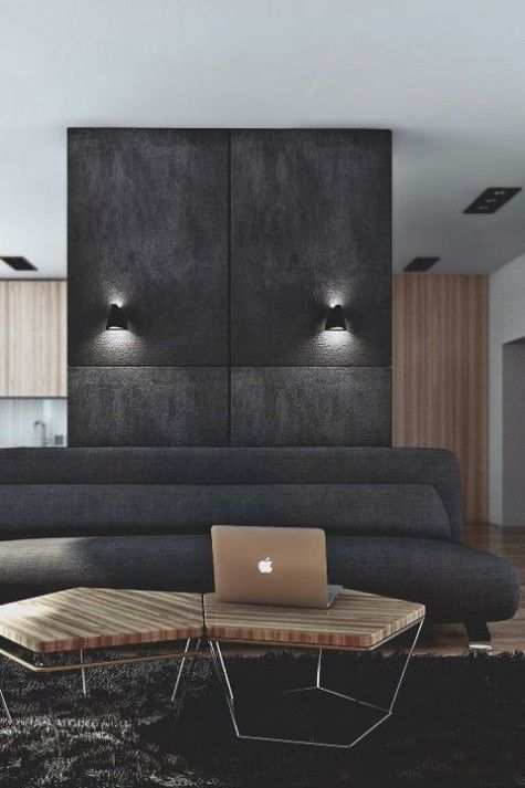 a minimalist masculine living room with a dark wall and sofa, a hex coffee table and lights