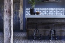 a navy kitchen with blue walls, a rug, printed tiles, a rough kitchen island with a stone countertop looks chic