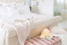 a pretty girlish bedroom done in white and light pink, with an upholstered bed and a pink bench, white bedding and lights