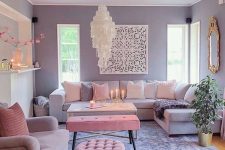 a pretty living room with lilac walls, a lilac sofa, a pink chair and a pouf, a pink bench, a catchy chandelier and a mirror in an ornated frame