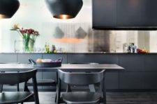 a refined and elegant black kitchen with a shiny backsplash, sleek cabinets, a dining set in black and catchy pendant lamps