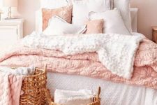 a relaxed feminine bedroom with blush walls, simple furniture, white and pink bedding, a shelf with art and a couple of baskets