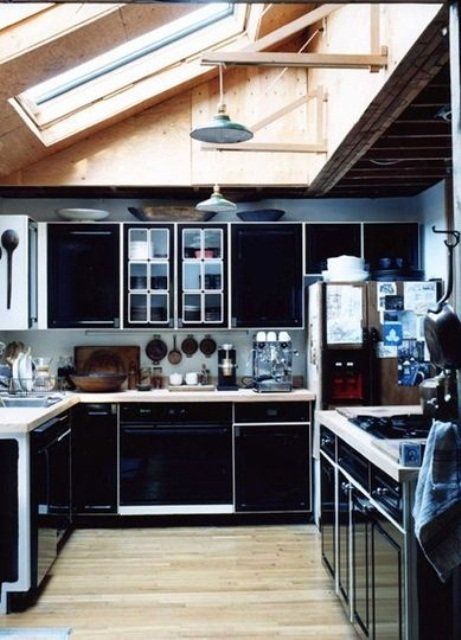 a sleek and refined black kitchen with white countertops and framing plus metal pendant lamps
