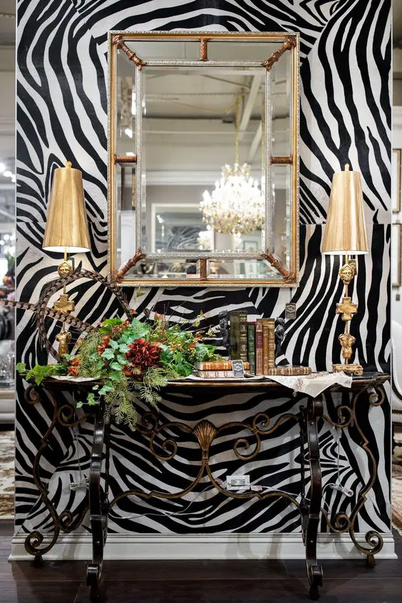 a sophisticated zebra print accent wall, a beautiful forged table, books and table lamps plus a gorgeous greenery arrangement on the table