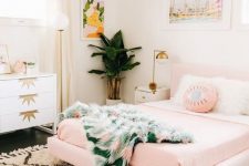 a tropical girlish bedroom with a pink floating bed, a printed rug and bedding, bold artworks and touches of gold