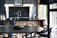 an elegant moody kitchen with a wooden kitchen island with a black countertop and a chalkboard plus pendant lamps