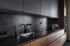 an ultra-minimalist kitchen with sleek black and rich-stained cabinets plus a sleek countertop plus a stone backsplash