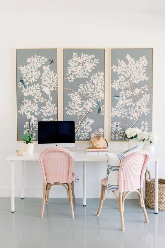 Beautiful light blue flora and fauna artworks and pink chairs make the home office spring like