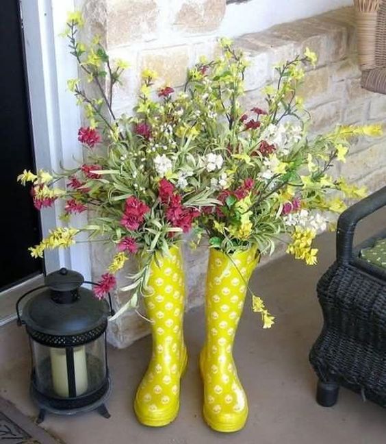 bright yellow rubber boots with a colorful floral arrangement and a candle lantern to welcome Easter