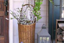 chic Easter porch decor with potted flowers, pussy willow in a basket and a large candle lantern