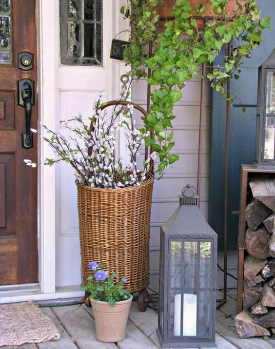 chic Easter porch decor with potted flowers, pussy willow in a basket and a large candle lantern