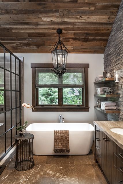 a barn bathroom with a reclaimed wooden ceiling, a tile floor, a stoen enclosed shower and a vintage lantern hanging down