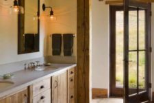 a barn bathroom with a wooden ceiling with beams, a wooden vanity, a stone countertop and vintage wall lamps