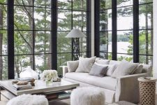 a beautiful barn living room with double-height windows, neutral furniture and a brown ottoman, faux fur stools is amazing