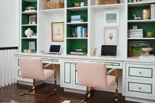 a bright and catchy home office with a large storage unit with emerald backing, blush chairs and gold touches